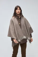 Ruana de lana sin teñir en tonos beige, con textura acanalada y terminaciones con flecos en los bordes.