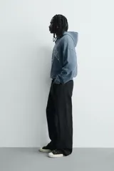 Sudadera tipo hoodie de corte relajado en color azul con efecto lavado. Presenta capucha, mangas largas, puños y ruedo en rib, con estampado frontal en color blanco con texto y números.