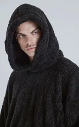 Hoodie oversize tipo anorak confeccionado en piel sintética de corderito, color negro. Presenta cierre central parcial, capucha ajustable con cordones y bolsillo canguro frontal.