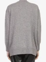 Cardigan de punto gris con escote en V, cierre frontal con broches ocultos y dos bolsillos frontales aplicados. Presenta puños y ruedo acanalados.