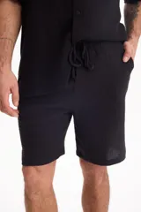 Bermuda negra de muselina con corte baggy, estilo deportivo y cordón ajustable en la cintura.