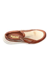 Zapatilla deportiva marrón de cuero liso con detalles en beige y plateado. Presenta cierre lateral y suela gruesa blanca.