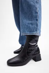 Bota de caña media con textura de reptil, color negro, con taco cuadrado bajo y punta redondeada.