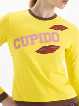 Remera de algodón pima con elastano, color rojo, de calce ajustado al cuerpo, manga larga y cuello redondo con detalles en color azul. Presenta estampa frontal con la palabra 'CUPIDO' y diseño de labios.