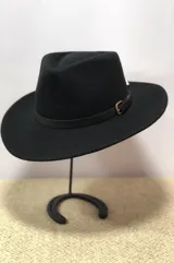 Sombrero de ala ancha confeccionado en lana impermeable, color negro, con cinta decorativa de cuero sintético y hebilla metálica.