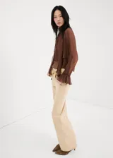 Blusa de viscosa color marrón chocolate, con diseño semitransparente, cuello alto y mangas largas con puños acampanados y volados.