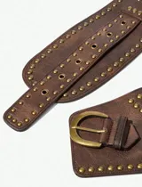 Cinto ancho de cuero marrón con tachas metálicas doradas, hebilla grande y diseño de doble correa.