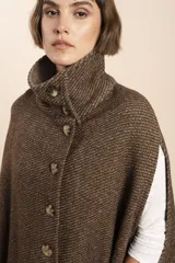 Capa color beige con textura de espiga, cuello alto con botones y aberturas laterales para los brazos. Confeccionada en lana fina sin teñir.