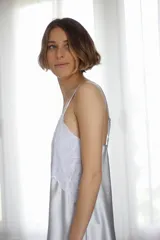 Camisón corto de satén color crema con detalles de puntilla gris en el escote y en el ruedo. Presenta breteles finos ajustables y un diseño fluido.