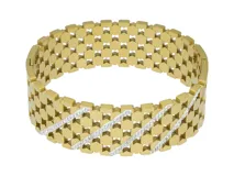 Pulsera tipo esclava rígida de acero con baño de oro, con diseño de malla calada y una línea central decorada con circonias brillantes.