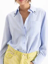 Camisa de poplín de tencel de silueta recta y calce holgado, con diseño a rayas celestes y verdes, cuello camisero con remaches en forma de corazón en las puntas, bolsillo frontal en el pecho y mangas largas con puños anchos.