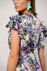 Vestido largo con estampado floral en tonos lila, verde y negro. Tiene escote en V, mangas cortas con volados y corte cruzado con lazo en la cintura.