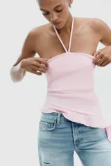 Top negro de cuello halter con lazada, escote recto y hombros descubiertos. Presenta un volante asimétrico en el lateral.