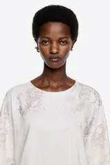 Remera de corte oversize con escote redondo y mangas cortas, confeccionada en algodón con un sutil estampado de textura animal print en tonos neutros.