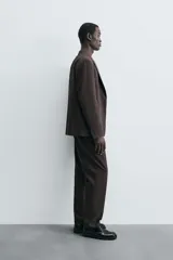 Blazer de corte regular fit confeccionado en tejido con lana. Presenta cuello con solapas de muesca, cierre frontal de un botón, bolsillos de vivo en el pecho y en la cadera, y aberturas en la espalda.