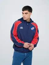 Campera deportiva Umbro del Club Nacional de Football, modelo Venti, para hombre. Diseño en color blanco con mangas azules y detalles de líneas rojas. Cuenta con capucha con cordón ajustable, cierre frontal y bolsillos. Presenta el logo de Umbro y el escudo del club bordados en el pecho.