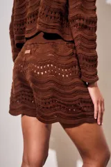 Short tejido de punto con diseño de ondas y calados, color blanco. Presenta cintura elástica acanalada y corte mini.