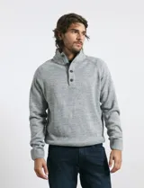 Sweater de punto color azul marino, con cuello alto, cierre frontal parcial y tapeta con botones. Presenta mangas raglán y puños y ruedo acanalados.