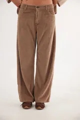 Pantalón de pana de algodón con corte ancho y cintura media-baja. Presenta bolsillos delanteros y traseros, cierre frontal con botón, y un aplique cuadrado decorativo en la parte inferior de una de las piernas.