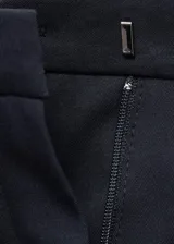 Pantalón de traje tiro medio, color azul marino, de diseño recto con trabillas, cierre oculto de botón, gancho y cremallera, dos bolsillos laterales y dos bolsillos de ribete en la parte posterior.