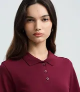 Blusa estilo polo de manga corta, confeccionada en tejido piquet color bordó. Presenta cuello clásico y cierre frontal con tres botones.