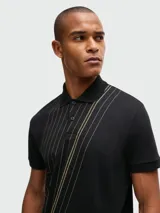 Polo de manga corta Boss confeccionada en algodón interlock, de color negro con estampado geométrico de líneas finas en tono dorado. Presenta cuello clásico con cierre de botones.
