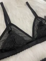 Conjunto de lencería compuesto por un corpiño triangular de microtul transparente con detalles de encaje en las copas y una tanga regulable de elástico ancho.