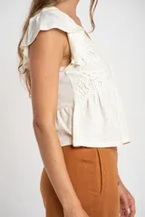 Remera color crudo de algodón con calados, corte al cuerpo y mangas cortas con volados.