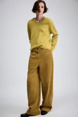 Pantalón de tiro medio confeccionado en tejido de pana, con diseño de pierna ancha, bolsillos delanteros y traseros, y cierre frontal con cremallera y botón.