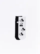 Pack de dos pares de medias, uno en color negro con diseño de rostro de Mickey Mouse y otro en color blanco con estampado de múltiples rostros de Mickey Mouse.