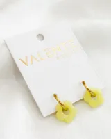 Par de aros Valente dorados con dije de flor color amarillo pastel. El aro es de acero y la flor de acrílico.