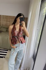 Chaleco top color verde azulado con efecto batik, escote halter con lazo ajustable, bolsillos frontales con hebillas metálicas y corte cropped.