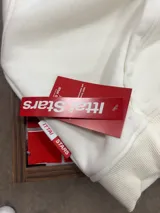 Buzo con cierre frontal completo, capucha amplia y bolsillos tipo canguro. Presenta estampado gráfico en el pecho con la marca IttaiStars y diseño de corte holgado.
