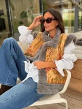 Chaleco de piel sintética en color gris, con diseño reversible. El interior presenta un forro de tela color mostaza con estampado floral bordado. Posee un corte holgado y sin mangas.