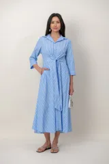 Vestido midi cruzado de seda con estampado de rayas celestes y blancas, escote en V con solapa, mangas tres cuartos y detalle de nudo drapeado en la cintura.