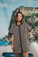 Vestido camisero corto, con cuello mao, botones a tono y parche con logo en el frente. Diseño a rayas verticales negras y blancas.
