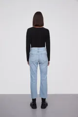 Pantalon jean de corte flare, tiro medio, con ruedo desflecado y cierre frontal con botón y cremallera.