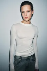 Top de punto fino y semitransparente color gris claro, con cuello redondo y manga larga.