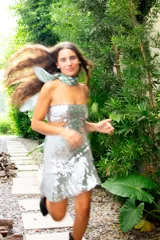 Vestido corto negro con diseño cut-out en la cintura, estilo strapless y ruedo decorado con flecos largos.