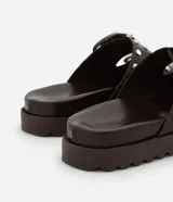 Sandalias planas flatform color marrón con puntera redonda, correas con hebillas plateadas y tachas redondas. Suela track.