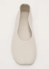 Zapato chatita de cuero ovino color beige, de diseño minimalista con punta redonda y suela de cuero.