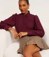 Camisa celeste de crepé con cuello inglés, manga larga abullonada y abotonadura frontal.