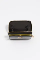 Billetera Bimba y Lola de estructura rígida con acabado efecto cocodrilo brillante en color negro. Cuenta con cierre de cremallera perimetral en contraste color verde lima y logo metálico dorado en el frente.