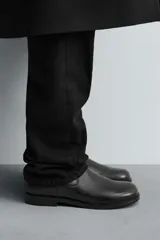 Bota de caña media fabricada en piel color marrón oscuro, con cierre de cremallera lateral, horma cuadrada y suela con ligero tacón.