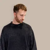 Buzo negro de corte oversize con efecto acid wash y bolsillos delanteros.