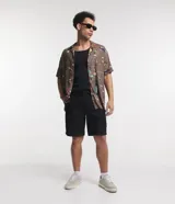 Bermuda masculina de corte slim, confeccionada en tejido de sarga de algodón. Presenta un diseño de sastrería con cierre de botón y cremallera, bolsillos laterales y traseros, y un acabado liso sin estampados.