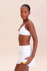 Pollera deportiva color rosa fucsia, con estampado en relieve de texto. Es de corte corto con ruedo redondeado y cuenta con shorts internos.