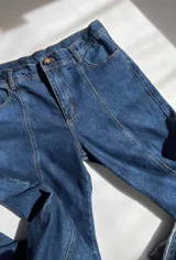 Jean de estilo recto y tiro medio-bajo confeccionado en denim azul marino oscuro. Presenta un diseño con costura vertical en la parte posterior de las piernas y bolsillos traseros clásicos. Esta prenda está elaborada con algodón reciclado bajo procesos de producción sostenible.