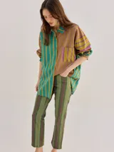 Camisa de algodón liviano con diseño de rayas multicolor, corte holgado, cuello camisero, mangas largas y bolsillo frontal.
