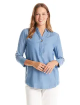 Blusa de lyocell color azul con efecto denim, cuello camisero con solapa y escote en V con cierre de un botón. Presenta mangas largas con terminación doblada y ruedo redondeado.